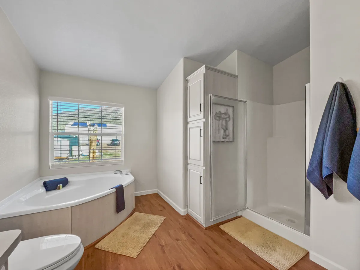 A serene bathroom featuring a luxurious standalone bathtub positioned near a window, with a separate shower area, vanity, and plenty of natural light. The scene evokes relaxation and a sense of pampered tranquility.