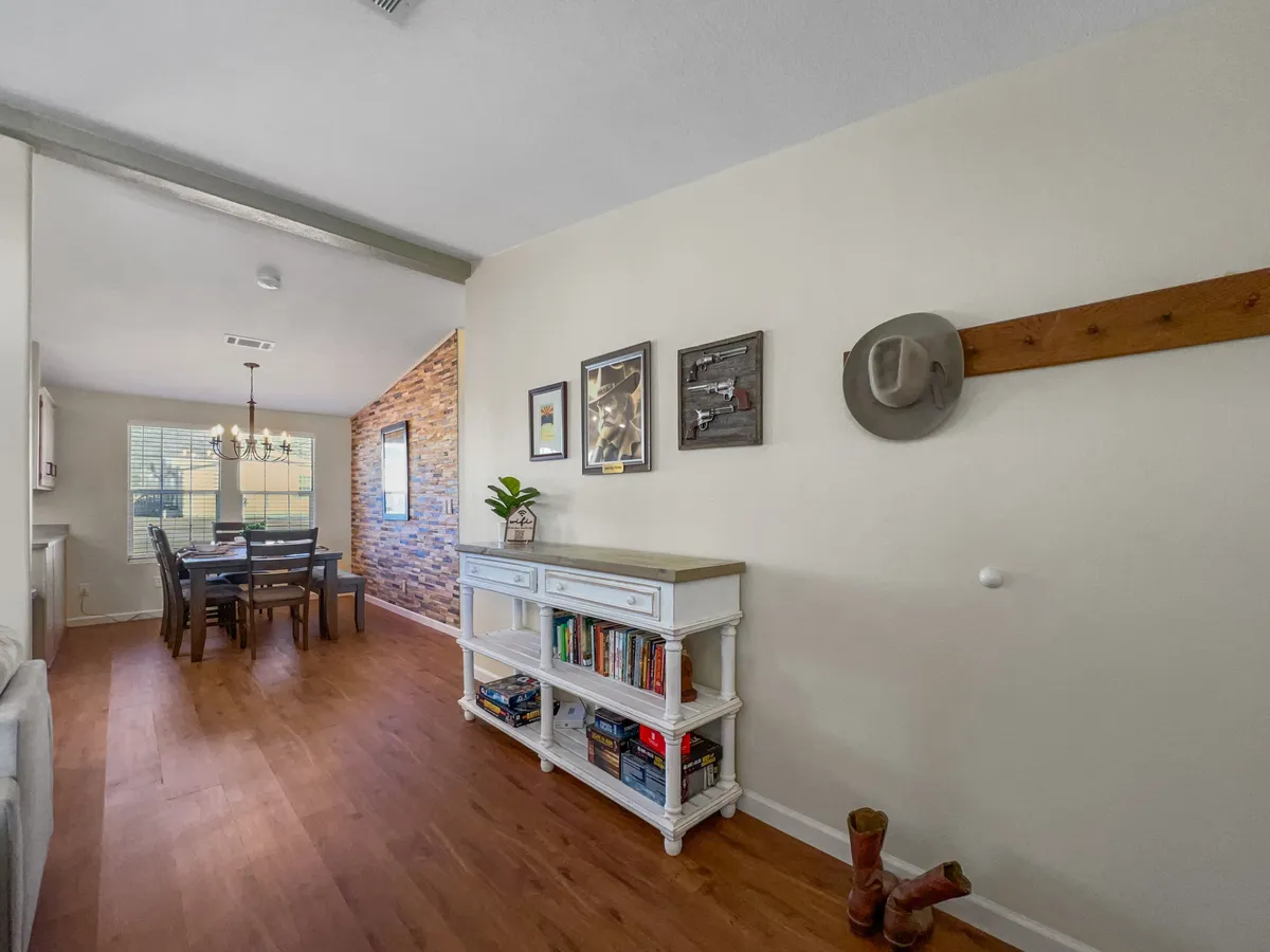 This image centers on a welcoming dining table, bookshelf, and framed artwork, creating a homey, inviting atmosphere. The space is designed for family gatherings, reading, dining, and entertaining, with subtle decor touches that evoke warmth and shared experiences.