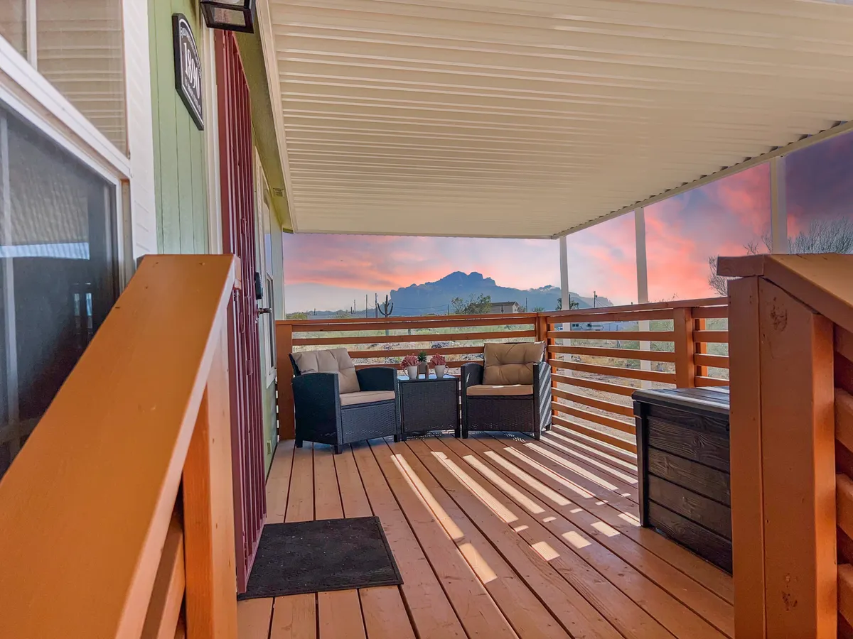 This image features a comfortable seating area set against a panoramic mountain view and a vibrant sunset sky. The outdoor lounge space encourages relaxation after a day’s adventure, with the dramatic mountains as a constant reminder of the area’s natural splendor.